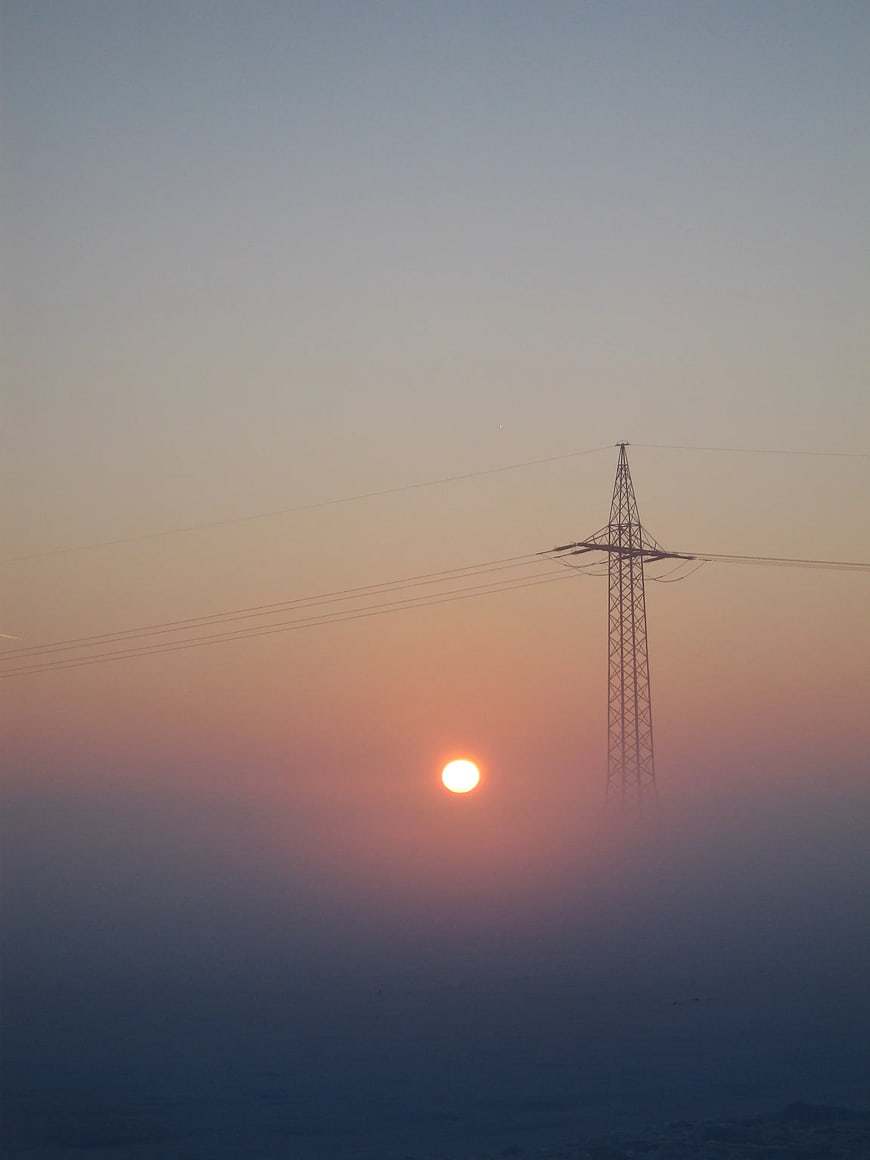 Silhouette of electricity pylon against sunset sky