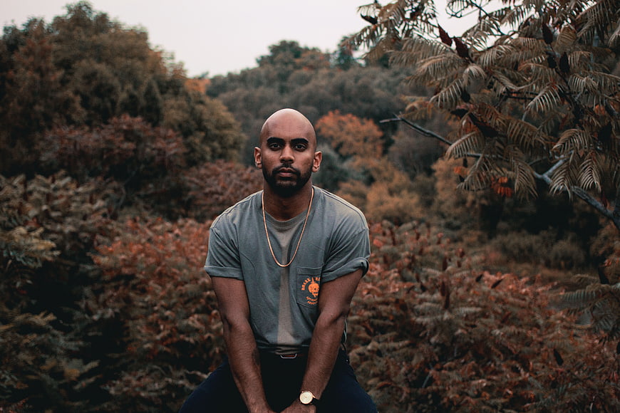 Portrait of bald man in grey t-shirt sitting in autumn forest