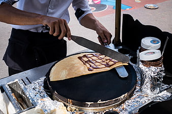 Street vendor preparing chocolate crepe on griddle