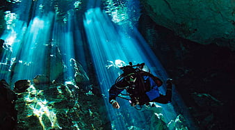 Scuba Diver Swimming Through Sunbeams In A Deep Blue Cenote