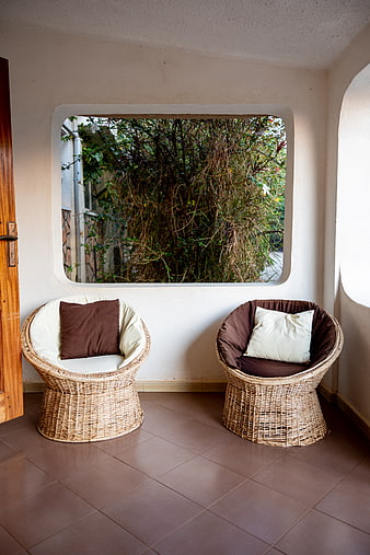 Cozy wicker chairs on a tiled patio with garden view