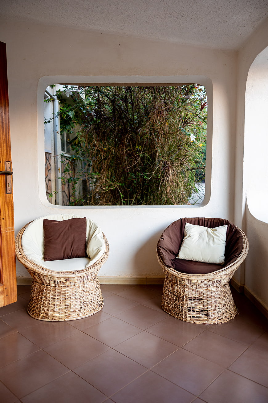 Cozy wicker chairs on a tiled patio with garden view