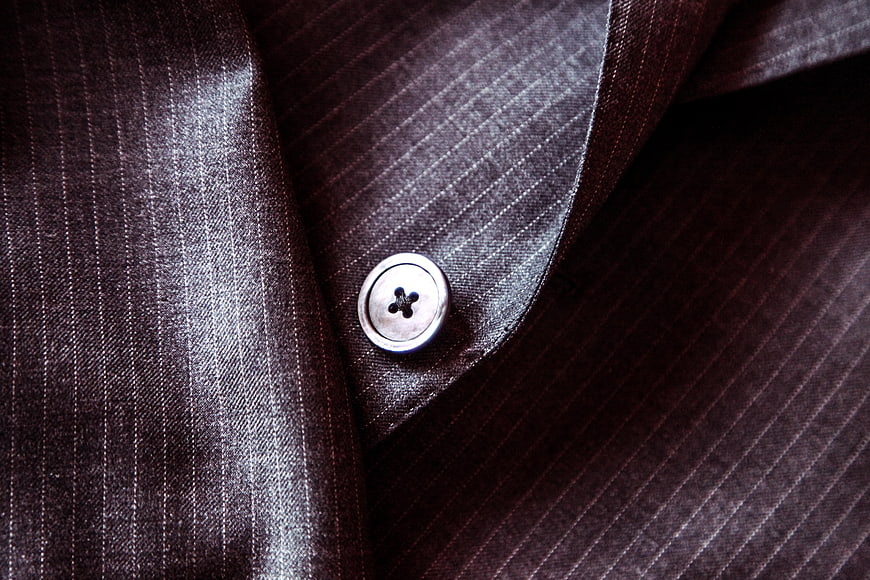 Close-up of dark pinstripe suit fabric with silver button