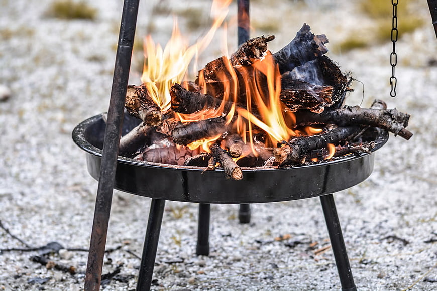 Campfire burning in metal fire pit on gravel ground