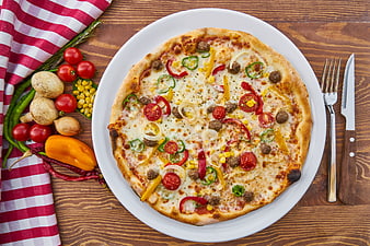 Top view of vegetable pizza on wooden table with fresh ingredients