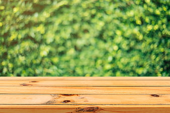 Empty wooden table surface with blurred green nature background