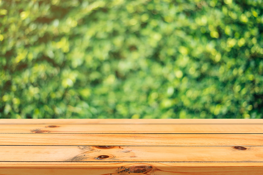 Empty wooden table surface with blurred green nature background