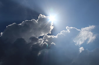 Dramatic Sunburst Behind Dark Storm Clouds in Blue Sky