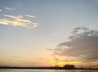 Sunset silhouette of bridge construction over calm water