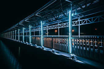 Modern LED-lit bridge structure at night with blue tones
