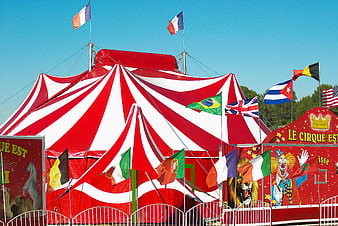 Red and white striped circus tent with international flags
