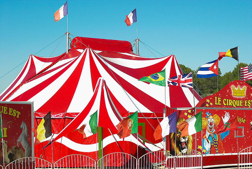 Red and white striped circus tent with international flags