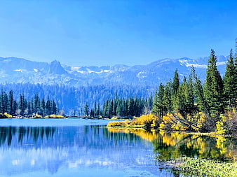 Serene autumn lake with yellow foliage and snow-capped mountains