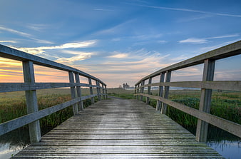 Wooden boardwalk bridge over marshland at sunrise