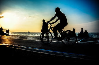 Silhouette of Cyclist Riding by Sea at Sunset
