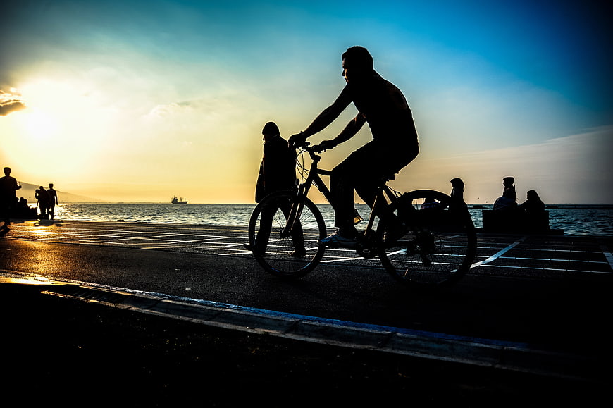 Silhouette of Cyclist Riding by Sea at Sunset