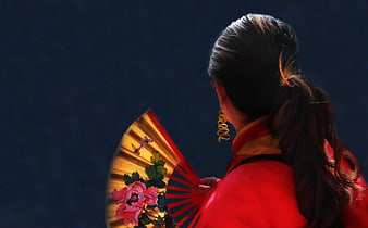 Woman in red dress holding traditional Chinese fan