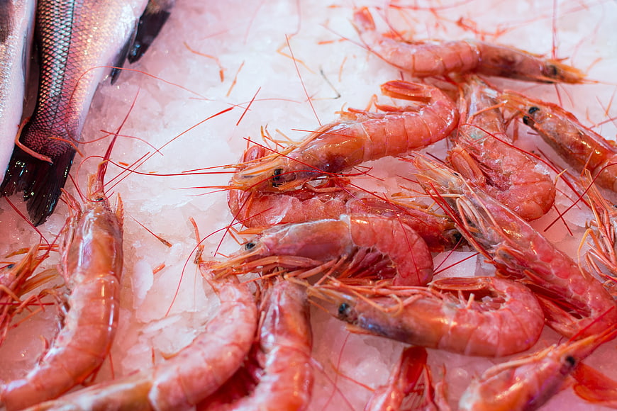 Fresh raw red prawns and fish on crushed ice