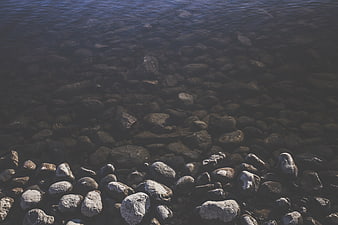 Dark moody pebbles in shallow clear water