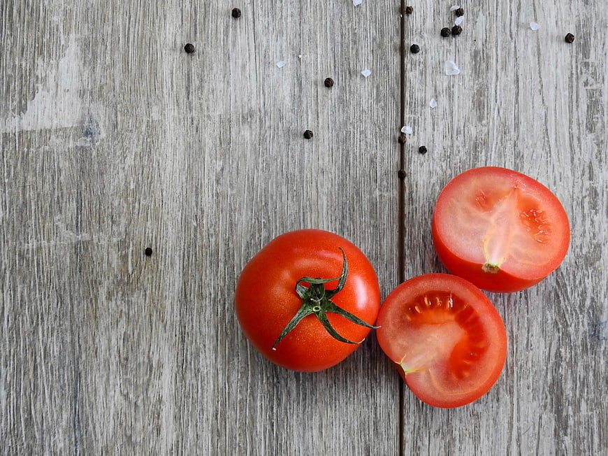 Fresh red tomatoes on rustic wooden background with salt and pepper
