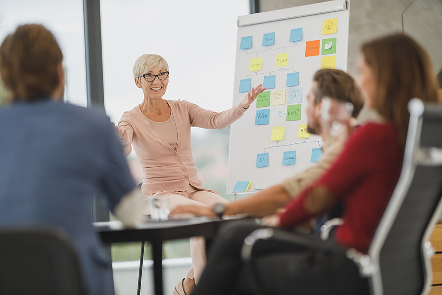 Senior Business Woman Leading Team Meeting with Whiteboard