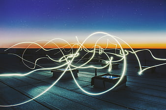 Abstract light painting trails on a rooftop at twilight