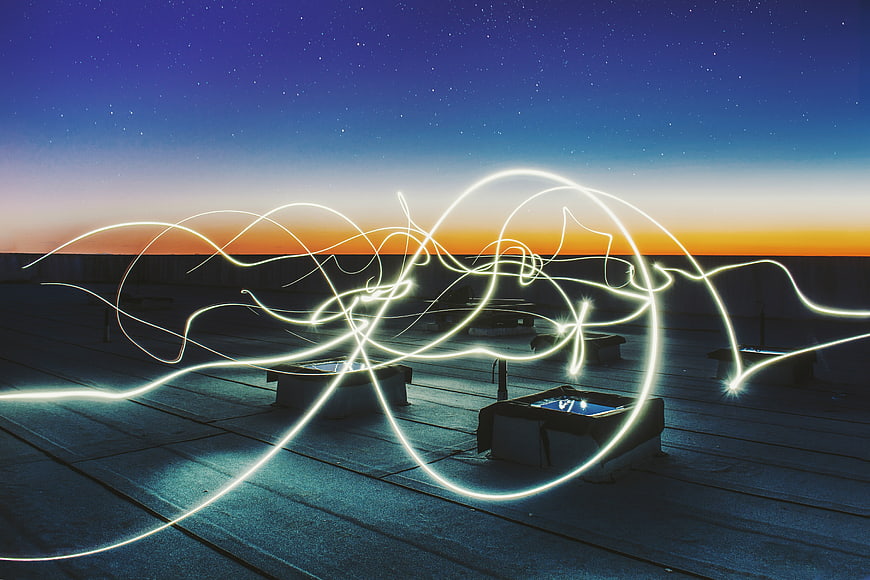 Abstract light painting trails on a rooftop at twilight