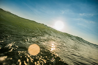 Dramatic Ocean Wave Crest With Sun Flare And Sparkling Water Surface