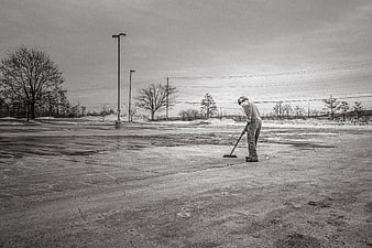 Man Sweeping Wet Concrete Parking Lot in Winter