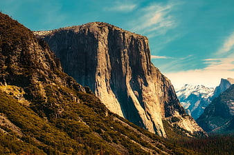 Majestic granite mountain peak with forested slopes and blue sky