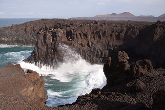Powerful ocean waves crashing into volcanic rock cliffs