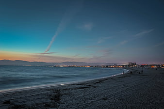 Long Exposure Sunset Beach with City Lights and Mountains