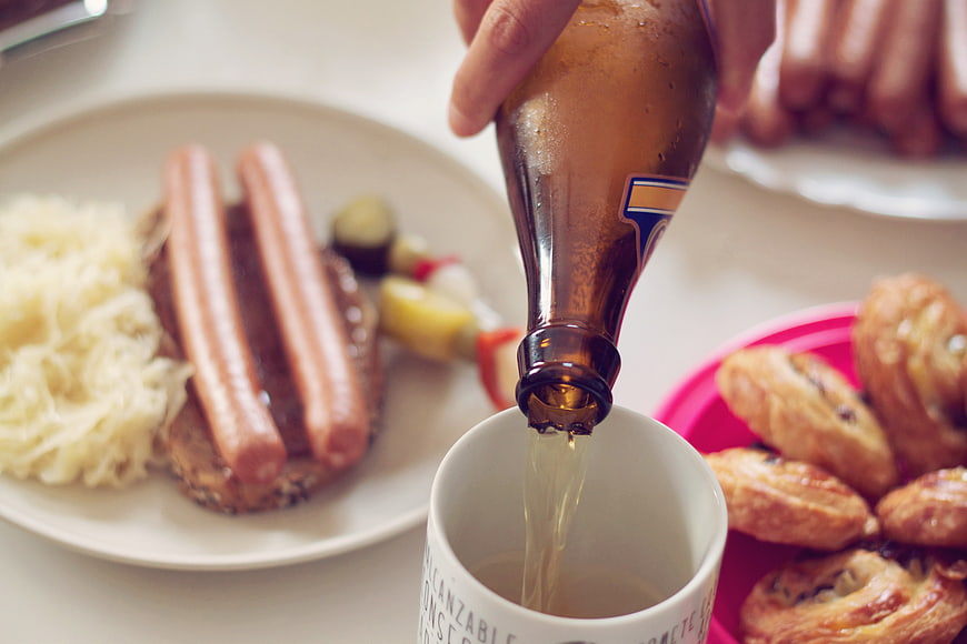 Pouring beer into a mug with sausages and pastries