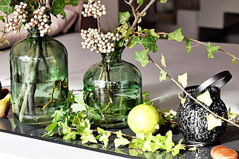 Green glass vases with ivy and berries on a table
