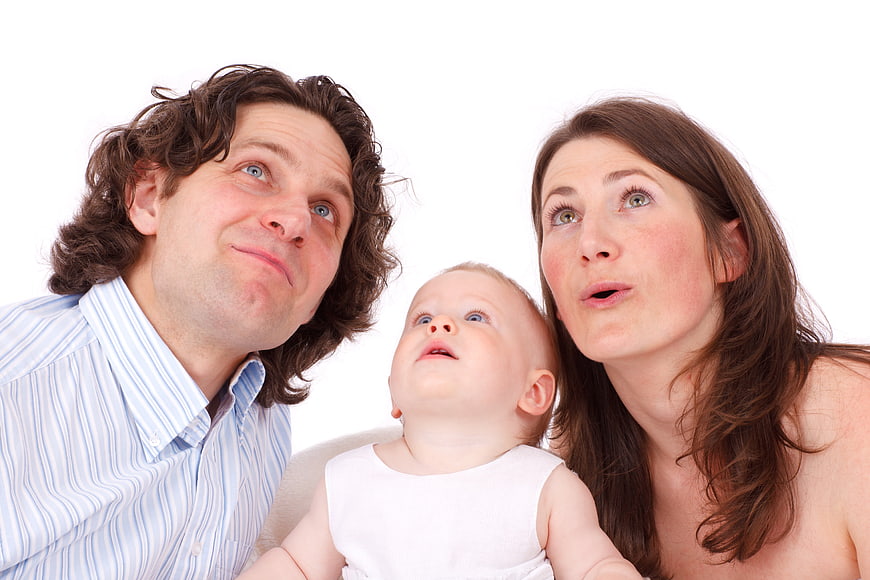 Family of three looking up with surprised expressions on white background