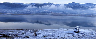 Panoramic winter landscape with boat on frozen lake shore