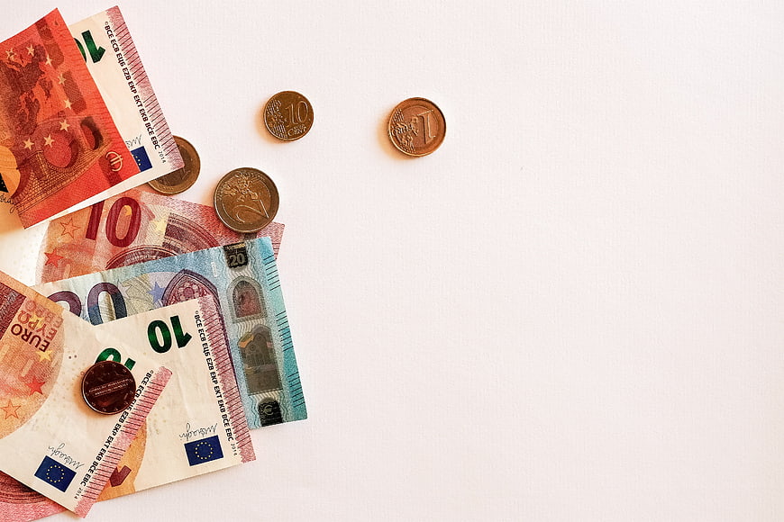 Euro banknotes and coins on white background with copyspace