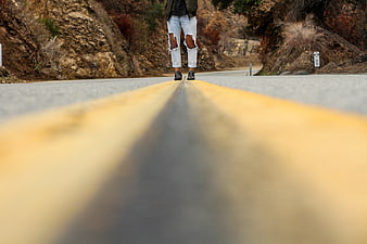 Person Walking on Yellow Road Lines in Nature