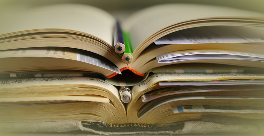 Stack of Open Books with Pencils and Notes