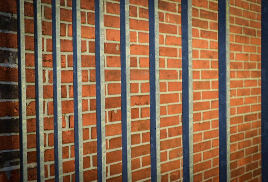 Vertical Metal Bars Against Red Brick Wall Background