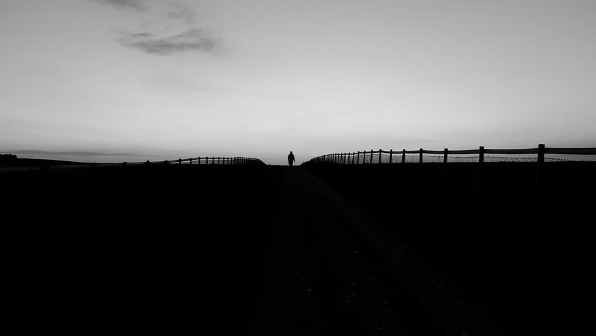 Silhouette of a person walking on a dark rural path