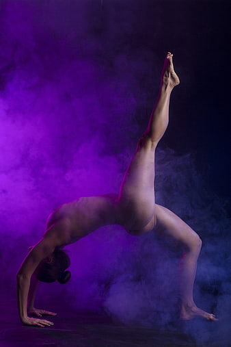 Nude female dancer performing backbend in purple smoke