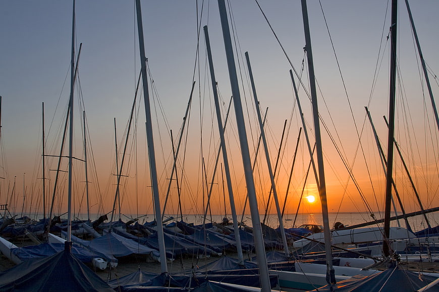 Sailboat Masts Silhouetted Against Orange Sunset Sky