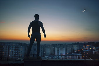 Silhouette of Man Standing on Rooftop at Sunset