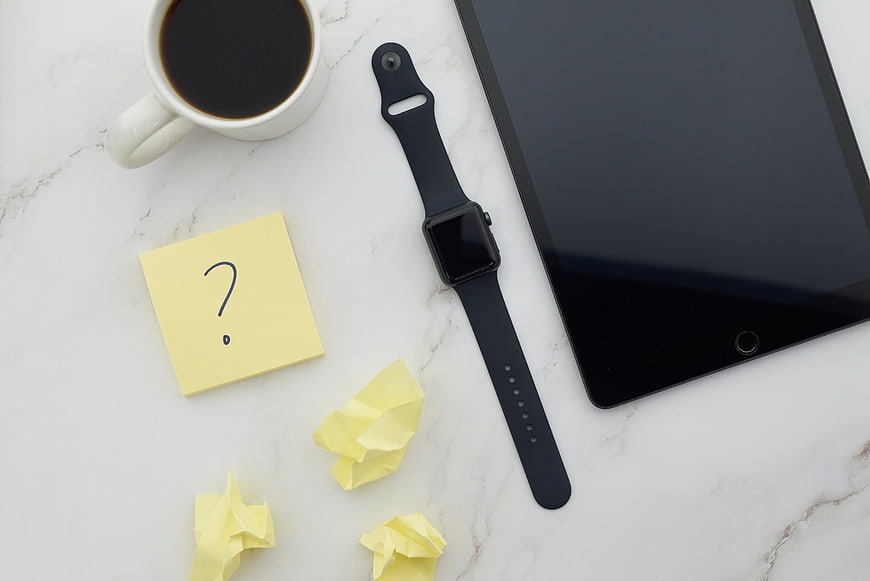 Flat lay of workspace with tablet, smartwatch, coffee, and sticky notes