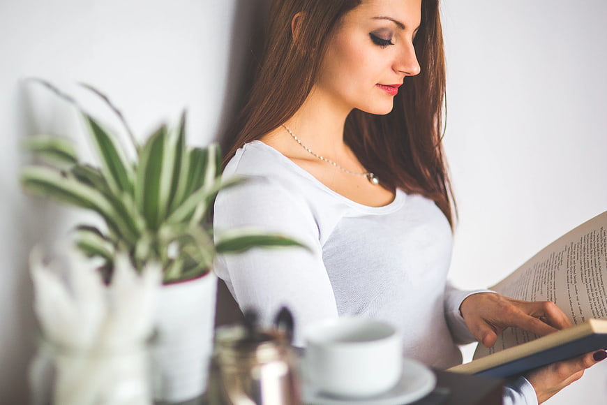 Young woman reading book at home with coffee