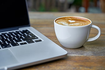 Latte with Heart Art Next to Laptop on Wooden Table