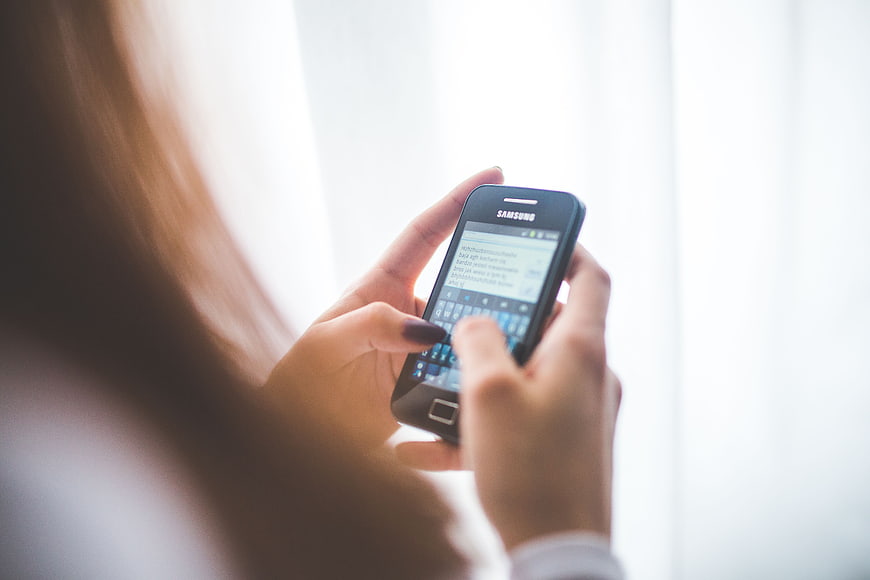 Woman typing on smartphone by window