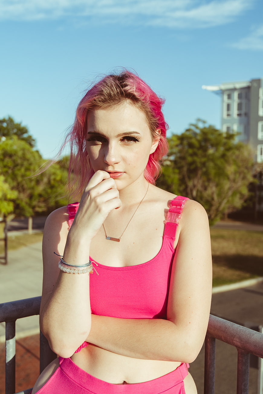 Young woman with pink hair in pink sportswear on balcony
