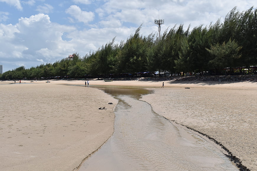 Sandy beach with winding stream and pine trees in Hua Hin